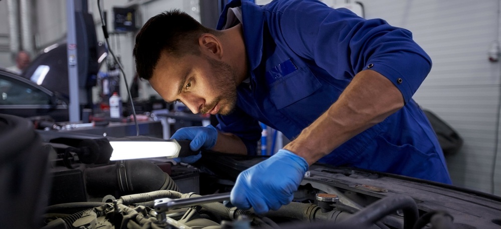 Automotive Service Technology- male mechanic working on a car under the hood