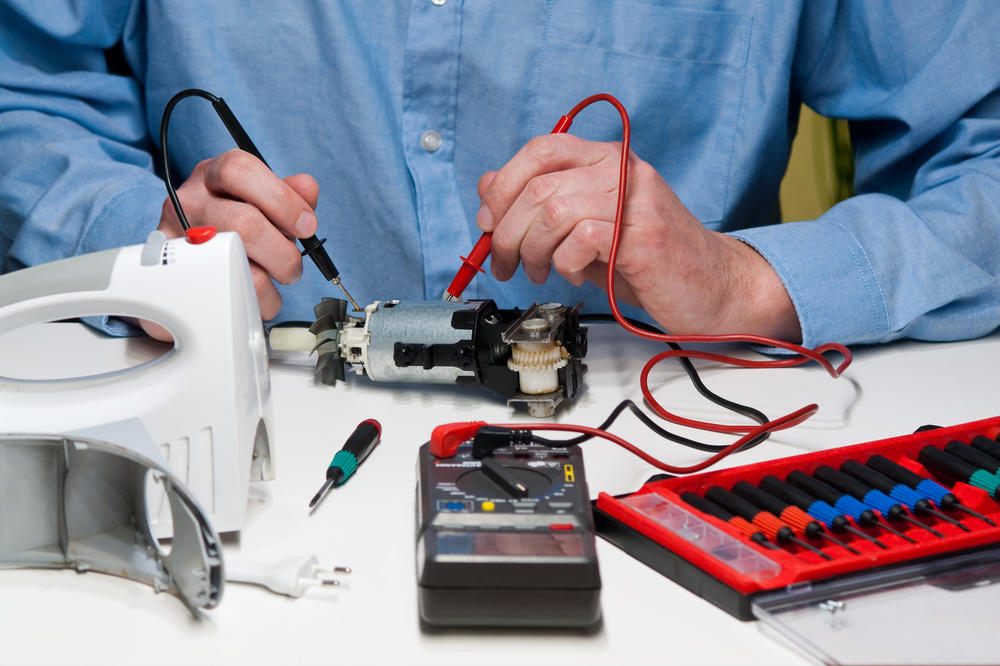 Major Appliance Service- Technician using a multimeter with red and black probes to measure voltage on a part