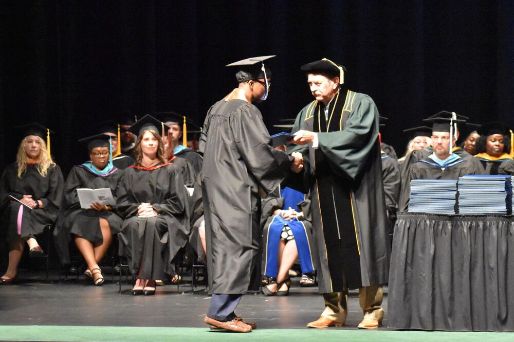 Courtland Bean receives diploma jacket from Board Chair, Brent Howton