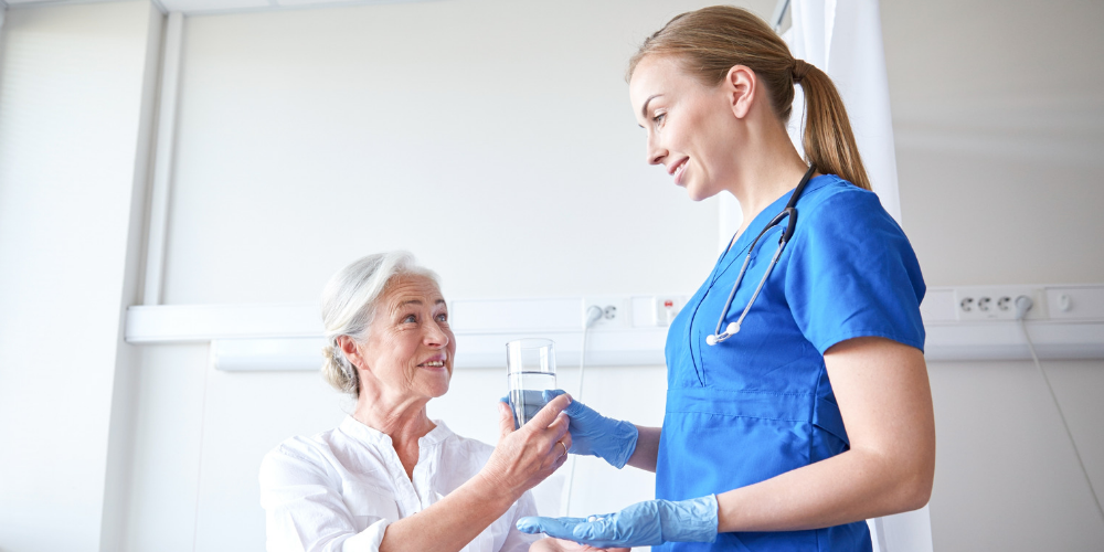Certified Nursing Assistant- Female nurse handing a female patient a glass of water