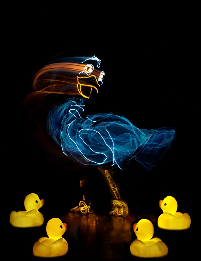 Ugly Duckling cover art on a black background with laser like overlays of ducks